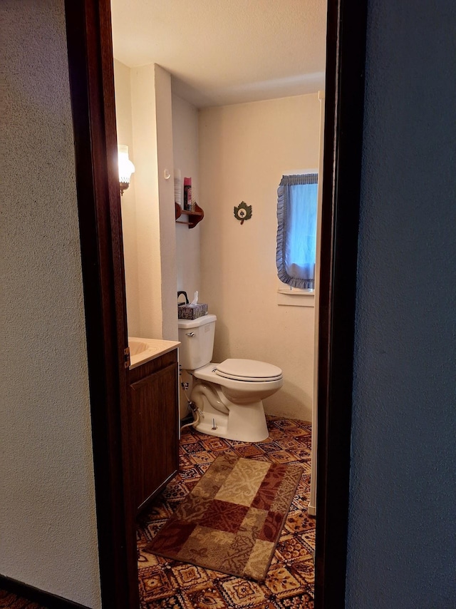 half bath featuring vanity and toilet