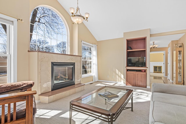 carpeted living area featuring a wealth of natural light, baseboards, a notable chandelier, and a tiled fireplace