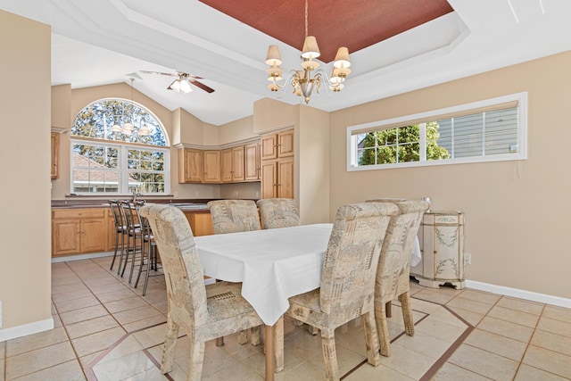 dining space with baseboards, a chandelier, lofted ceiling, light tile patterned floors, and a raised ceiling