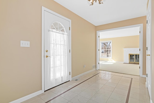 entryway featuring visible vents, baseboards, an inviting chandelier, and a glass covered fireplace