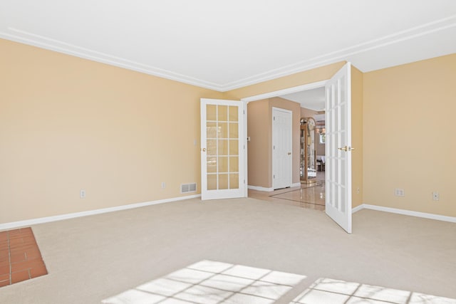 spare room with light colored carpet, french doors, visible vents, and baseboards