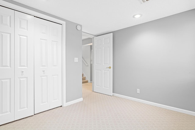 unfurnished bedroom featuring a closet, baseboards, and light colored carpet