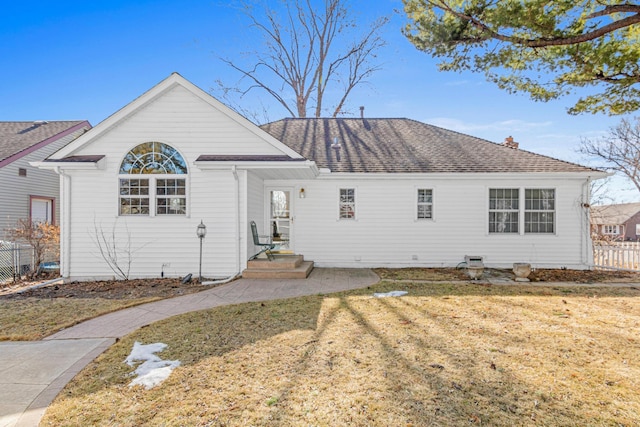 exterior space with a shingled roof, a yard, and fence