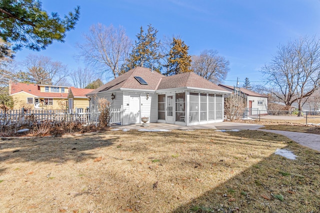 back of property featuring fence, roof with shingles, a lawn, a sunroom, and a patio area