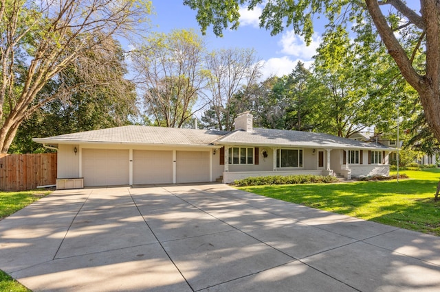 ranch-style home featuring a garage, fence, concrete driveway, a front lawn, and a chimney