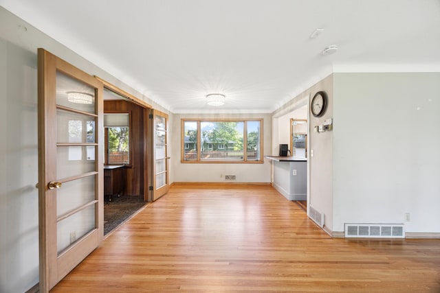 interior space with light wood-style floors, baseboards, visible vents, and french doors