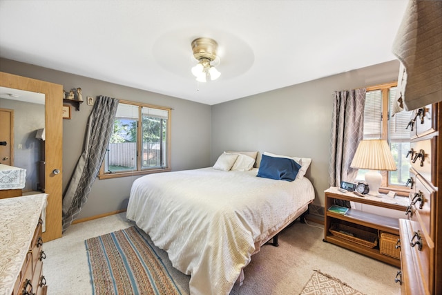 bedroom featuring multiple windows, ceiling fan, light carpet, and baseboards