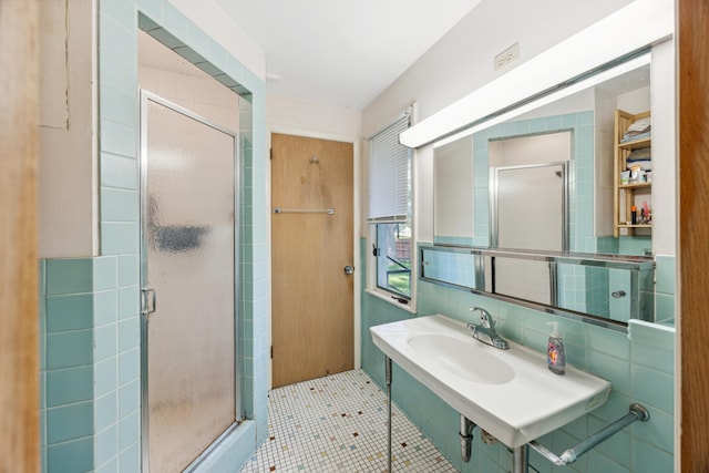 full bathroom featuring tile walls, backsplash, tile patterned flooring, a shower stall, and a sink