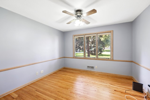 empty room with visible vents, ceiling fan, baseboards, and wood finished floors