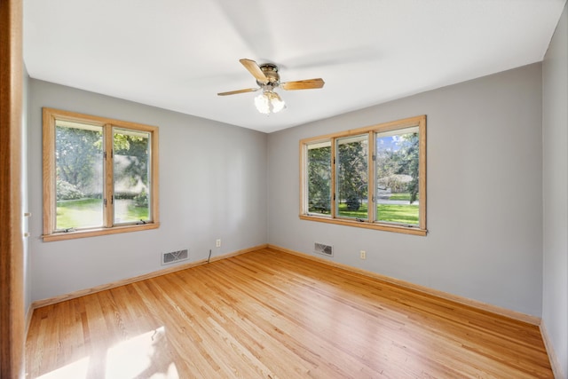 spare room featuring wood finished floors, visible vents, and a healthy amount of sunlight