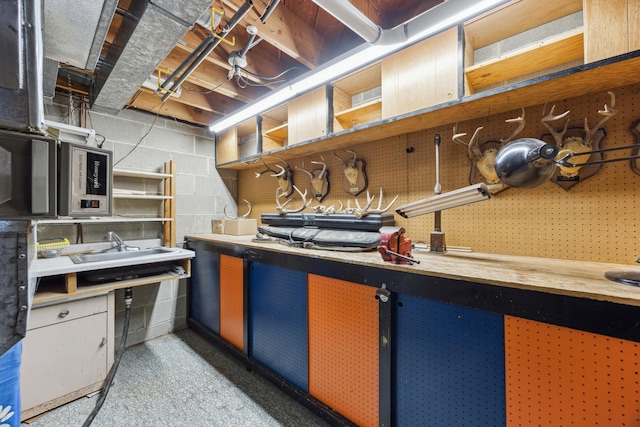 kitchen with open shelves, stainless steel microwave, light countertops, and concrete block wall