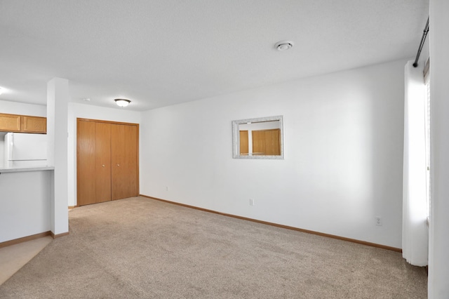 spare room with baseboards and light colored carpet