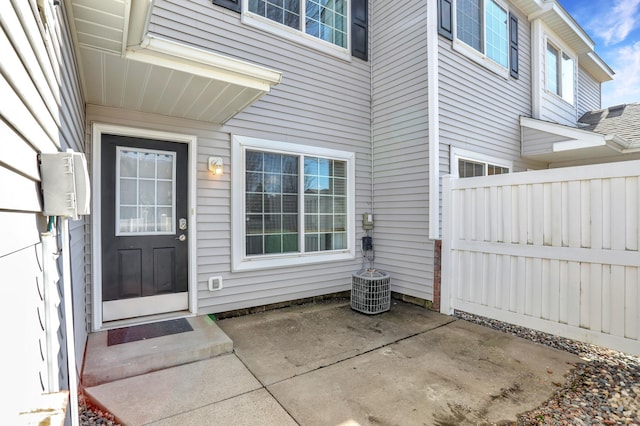 view of exterior entry with a patio and fence