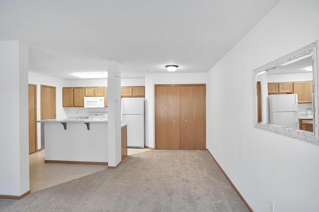 kitchen with light countertops, white appliances, light carpet, and a breakfast bar area
