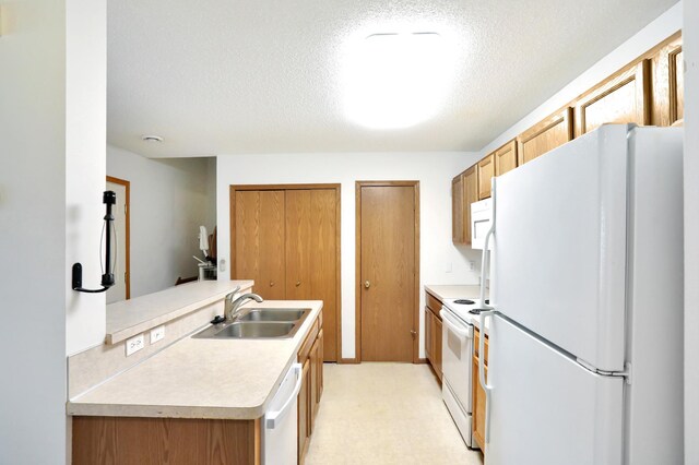 kitchen featuring light floors, light countertops, a sink, a textured ceiling, and white appliances