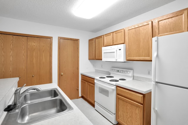 kitchen featuring a textured ceiling, light countertops, white appliances, and a sink