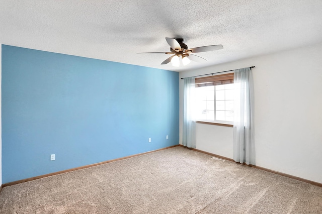 carpeted empty room featuring ceiling fan, a textured ceiling, and baseboards