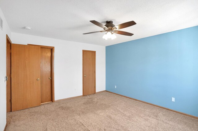 unfurnished bedroom featuring a ceiling fan, carpet, a textured ceiling, and baseboards