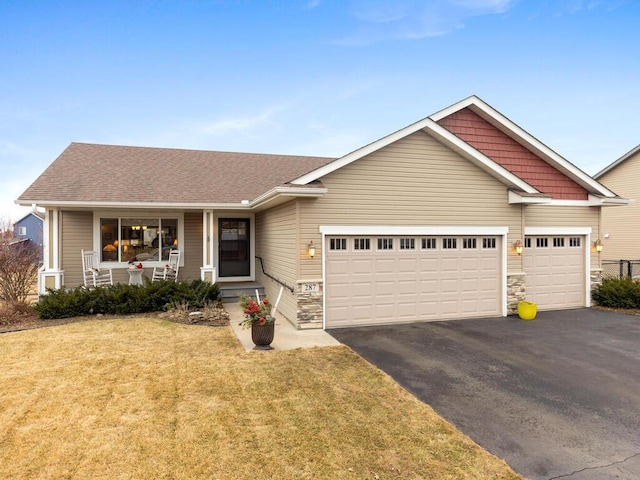 ranch-style house with covered porch, an attached garage, a front yard, stone siding, and driveway