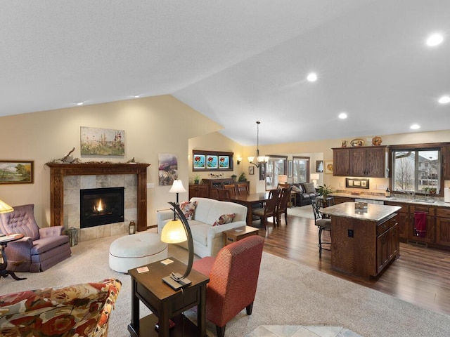 living area featuring dark wood-type flooring, recessed lighting, a fireplace, and vaulted ceiling