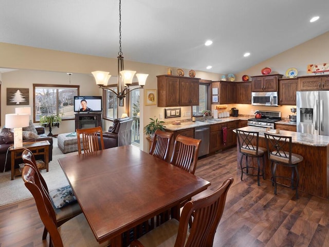 dining room with lofted ceiling, a notable chandelier, dark wood finished floors, and recessed lighting