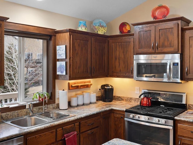 kitchen featuring lofted ceiling, light countertops, appliances with stainless steel finishes, and a sink