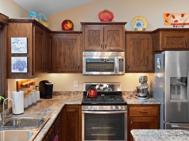 kitchen featuring stainless steel appliances, lofted ceiling, and a sink