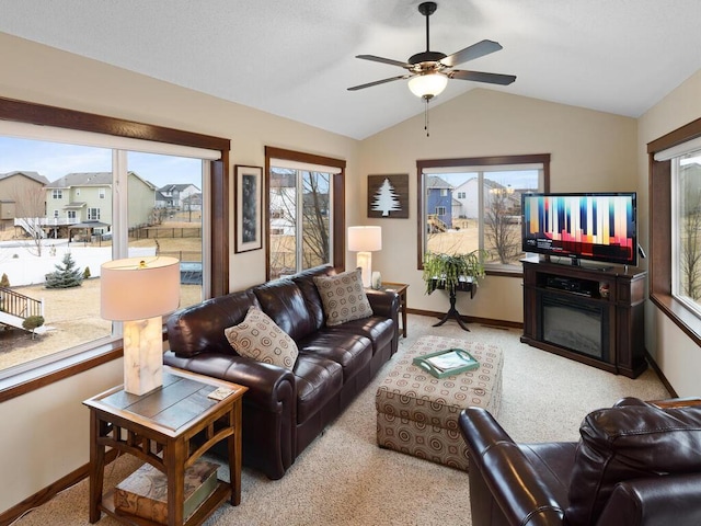 living area featuring light colored carpet, baseboards, vaulted ceiling, and a glass covered fireplace