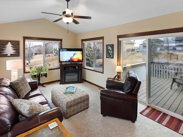 carpeted living room featuring a glass covered fireplace, vaulted ceiling, baseboards, and ceiling fan