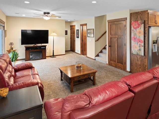 living area featuring recessed lighting, light carpet, a ceiling fan, baseboards, and stairs