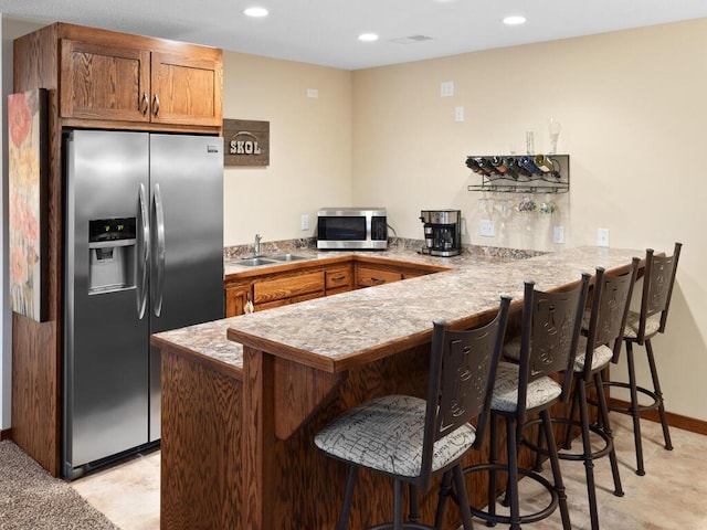 kitchen with a peninsula, appliances with stainless steel finishes, light countertops, and a sink