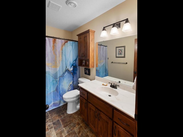 full bath featuring toilet, a shower with shower curtain, vanity, visible vents, and stone finish flooring