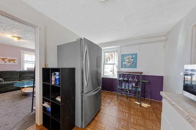 kitchen with a wealth of natural light, freestanding refrigerator, and a textured ceiling