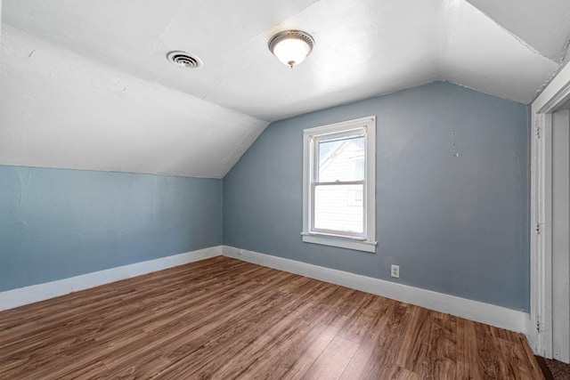 bonus room with visible vents, vaulted ceiling, baseboards, and wood finished floors