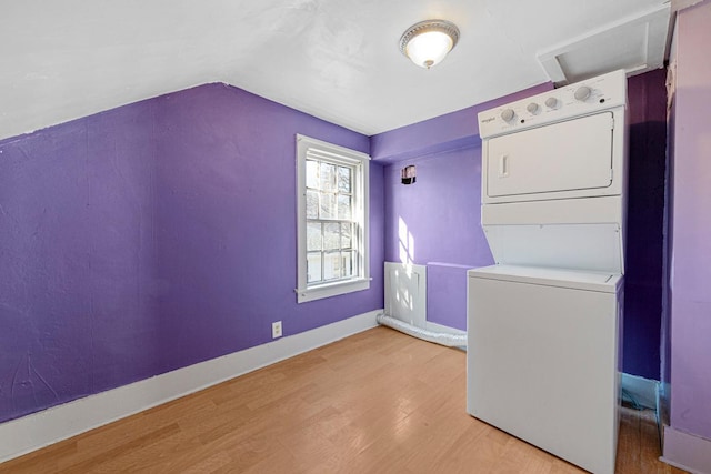 laundry area with stacked washing maching and dryer, laundry area, baseboards, and wood finished floors