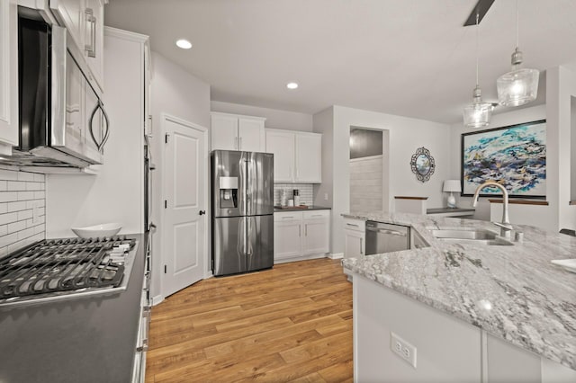 kitchen with white cabinetry, stainless steel appliances, light wood-type flooring, and a sink