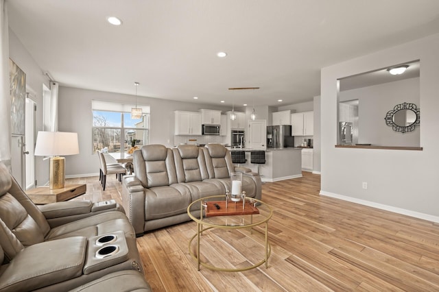 living area with recessed lighting, light wood-type flooring, and baseboards