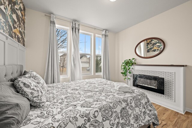 bedroom with a glass covered fireplace, baseboards, and wood finished floors