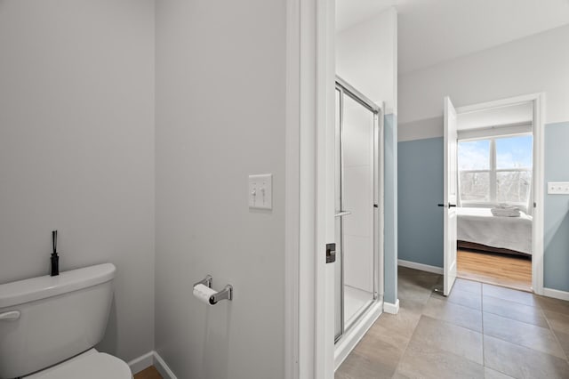 bathroom with tile patterned floors, toilet, a stall shower, ensuite bath, and baseboards