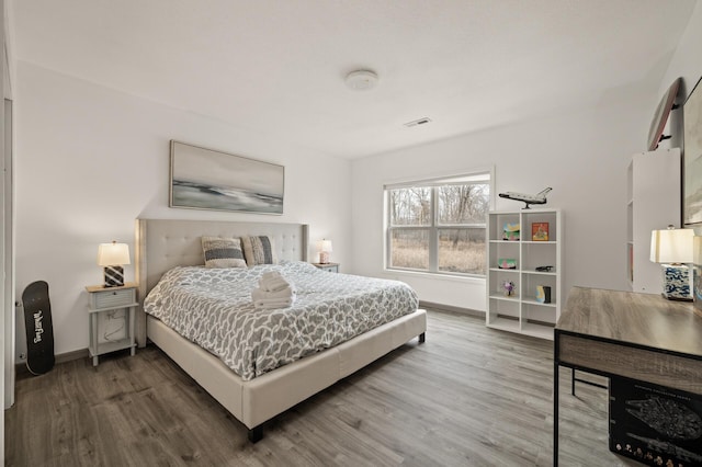 bedroom with visible vents, baseboards, and wood finished floors