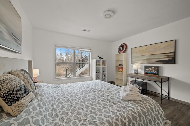 bedroom featuring visible vents, baseboards, and wood finished floors