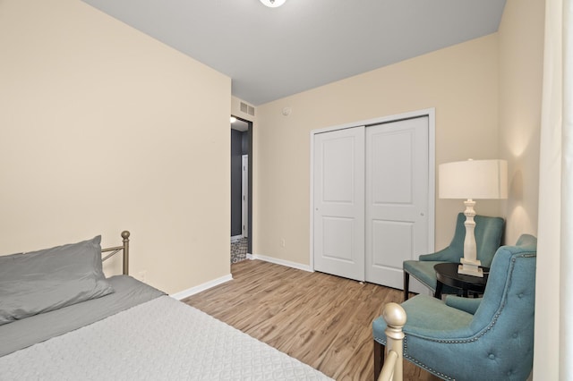 bedroom with a closet, visible vents, baseboards, and wood finished floors