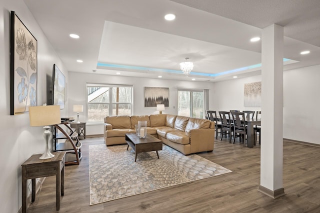 living area with recessed lighting, baseboards, a tray ceiling, and wood finished floors