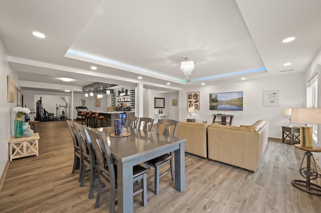 dining space with a tray ceiling, recessed lighting, and light wood-style floors