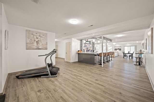 workout area featuring a bar, wood finished floors, visible vents, and baseboards