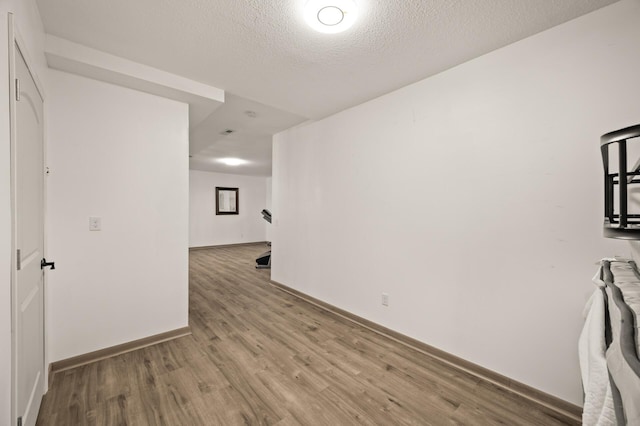 spare room with a textured ceiling, baseboards, and wood finished floors