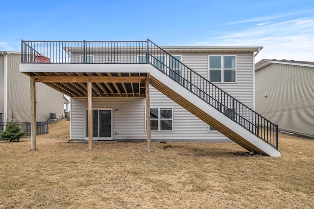 back of property featuring a lawn, a wooden deck, and stairs