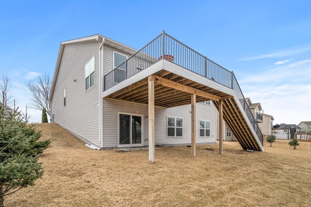 rear view of house featuring a deck, stairway, and a lawn