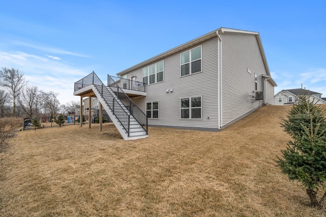 rear view of house featuring a deck, stairs, a yard, and fence