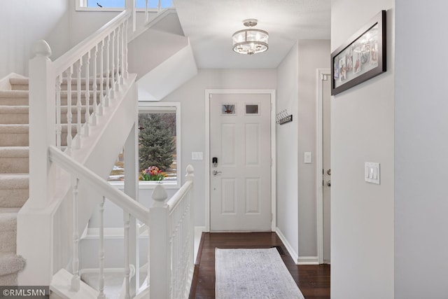 foyer entrance featuring stairs, baseboards, and dark wood-style flooring